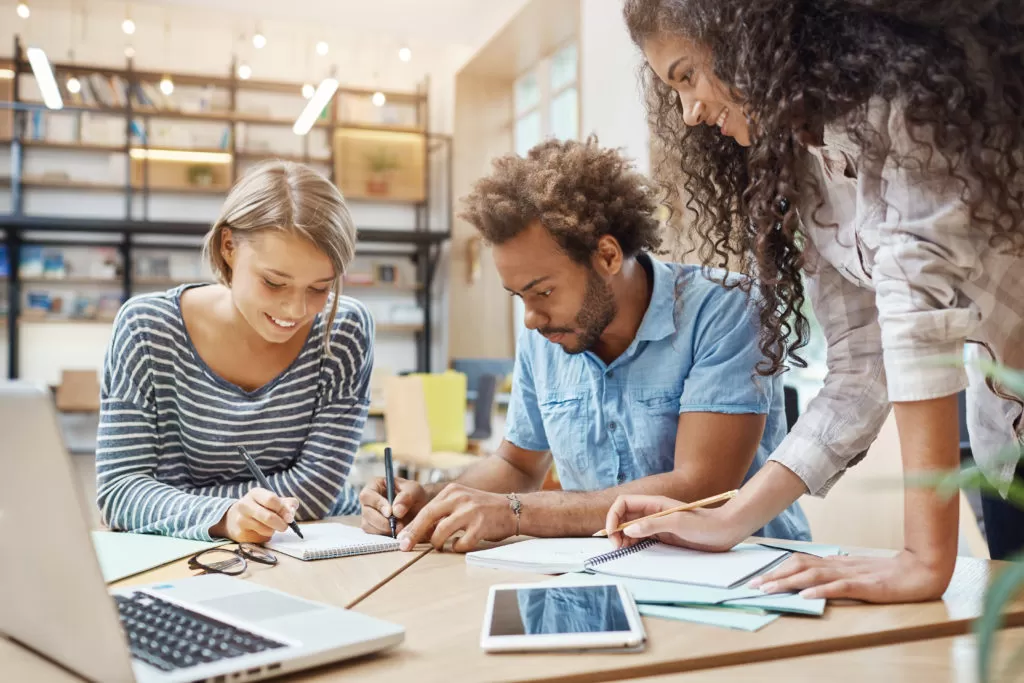Diverse group of young professionals collaboratively discussing over a laptop in a creative workspace.