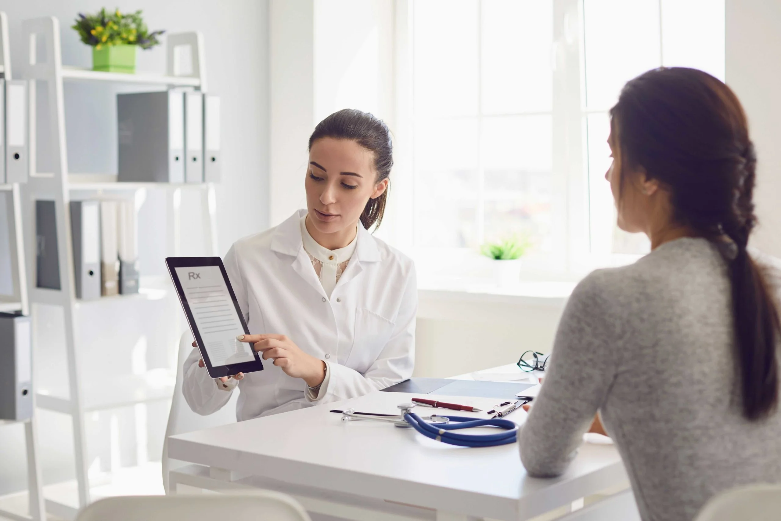 Healthcare professional explaining digital prescription to a patient using a tablet in a bright clinic setting