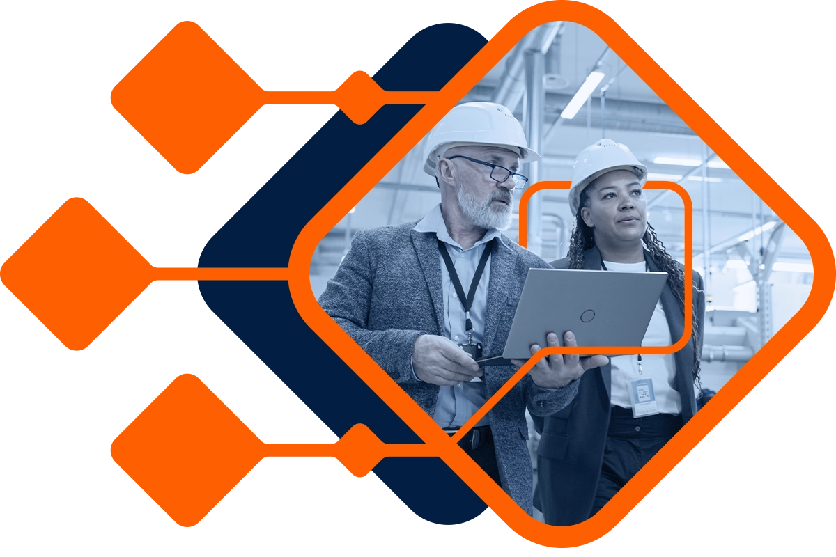 Senior engineer and young manager analyzing data on tablet in a manufacturing plant.